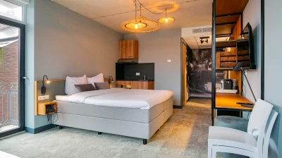 Overzicht van de Suite in Hotel Marktstad met keuken, tweepersoons king size bed, industriële kast, flatscreen televisie en tafel met twee stoelen