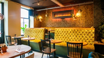 Restaurant tafels en een gouden bank in Grand Cafe Restaurant de Ooievaar